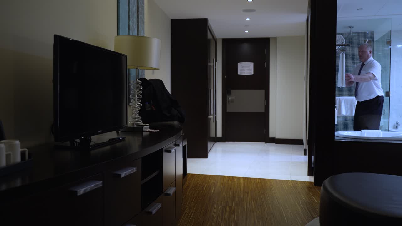 한 사업가가 자신의 호텔 방에서 체크아웃하기 위해 정장 코트와 짐을 모은다