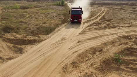 red dump truck driving on a quarry dirt road