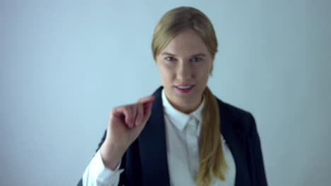 Fancy-business-girl-pointing-with-finger-toward-camera-in-studio-with-white-background