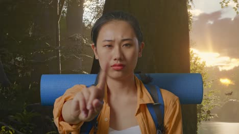 close up of asian female hiker with mountaineering backpack showing no gesture with index finger while exploring forest nature