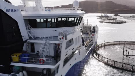 Close-up-drone-shot-of-a-fish-farming-vessel-docked-to-a-fishing-cage