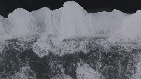 Luftaufnahme-Von-Oben-über-Die-Meereswellen,-Die-Am-Schwarzen-Sandstrand-Von-Island-Sólheimasandur-Krachen