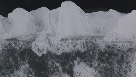 aerial top view over ocean waves crashing on iceland sólheimasandur black sand beach