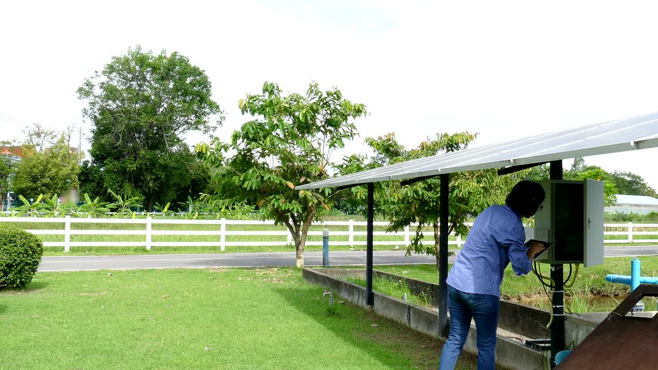 농업 전문가는 농장에서 물을 핑하기 위해 태양 전지를 모니터링하기 위해 태블릿을 사용합니다. 모바일 앱 기술을 사용하여 농업에서 전력 관리를합니다.