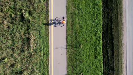 Disparo-De-Drones-Aéreos-De-Mujeres-Ciclistas-Con-Una-Chaqueta-Muy-Visible-En-Una-Carretera-De-Bicicletas