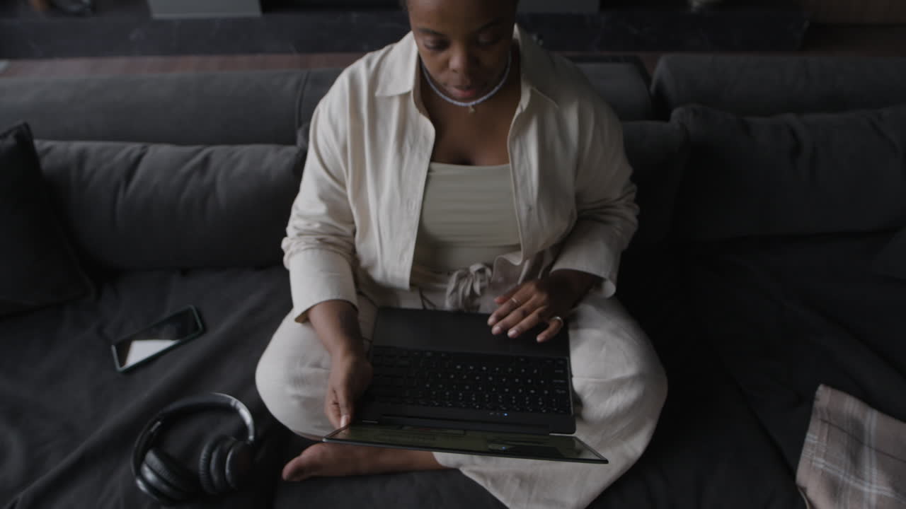 Woman sitting on couch using laptop