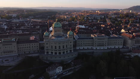 Toma-Aérea-Giratoria-Del-Edificio-Del-Parlamento-En-Berna,-Suiza-Al-Atardecer