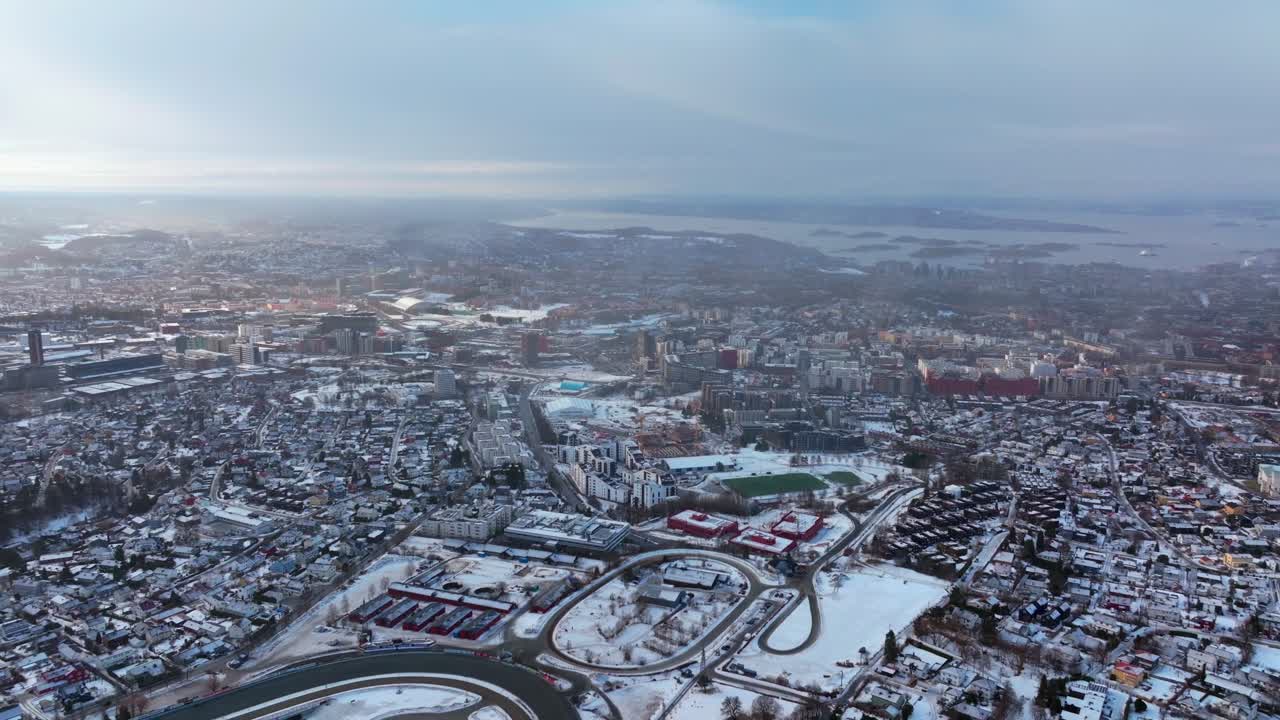 Winter city center downtown Oslo Norway Norge downtown OsloFjord sea water Fjord arctic circle Scandinavia Gamle Hovedoya early morning snowy cloudy buildings cars highway roads backwards