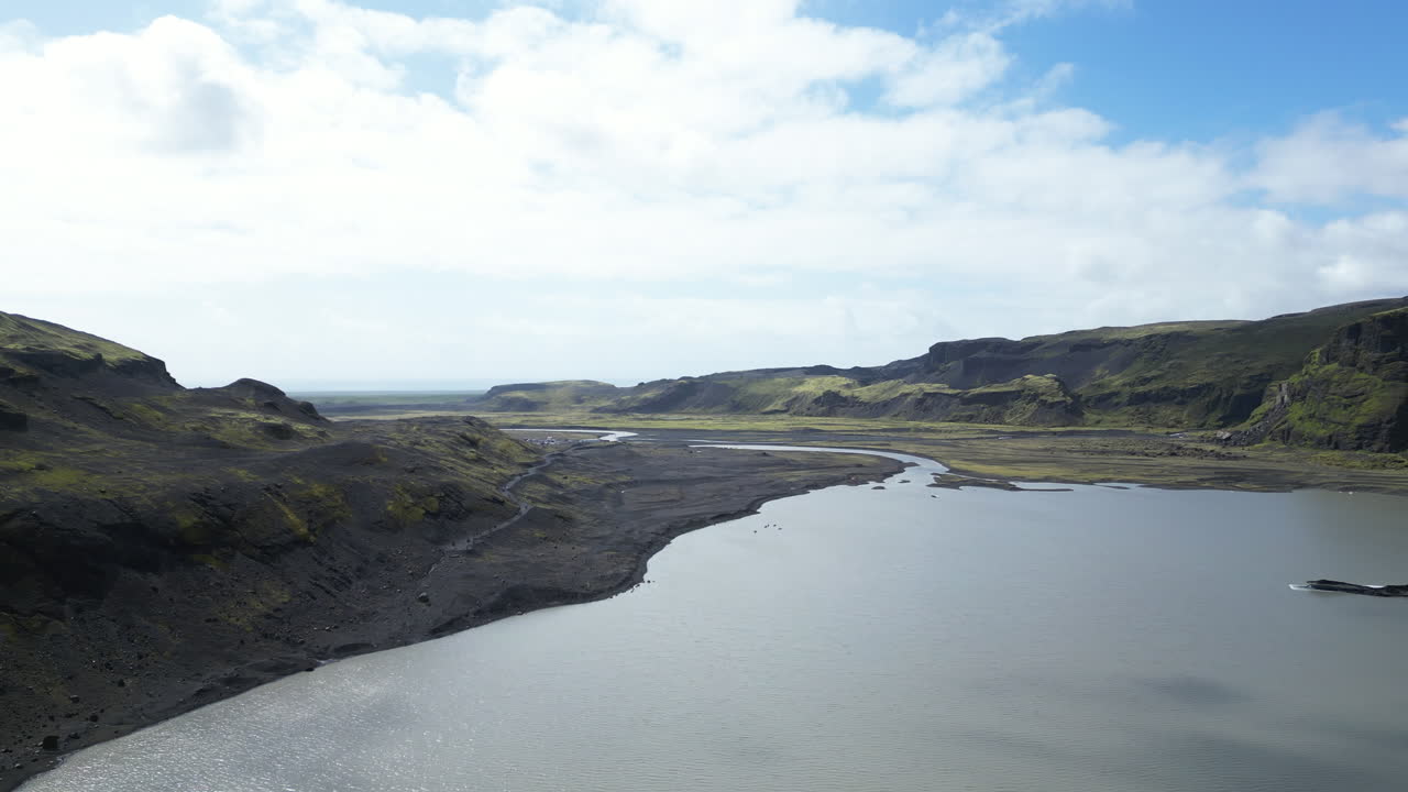Mountain lake surrounded by rocky slopes under bright daylight from above, Sólheimajökull, Iceland