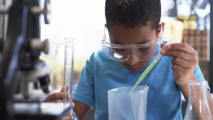 In un'aula di laboratorio scientifico scolastico, uno studente afroamericano conduce un esperimento.