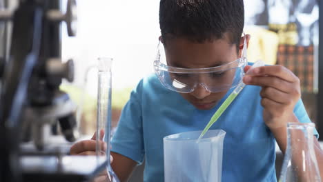 in a school science lab classroom, an african american student conducts an experiment