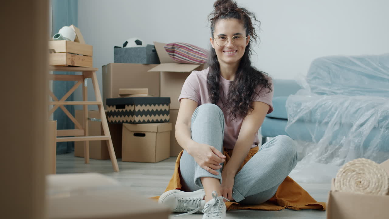 Woman sitting on floor among moving boxes