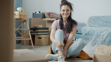 woman sitting on floor among moving boxes