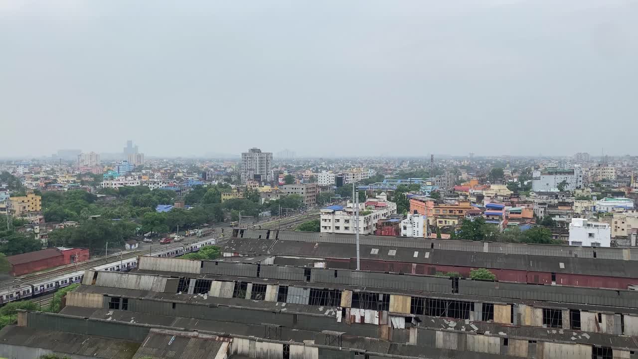 Spettacolare vista aerea della magnifica città di Kolkata con binari ferroviari, vecchie fabbriche dismesse e un treno in movimento.