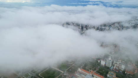aerial video of phnom penh shows clouds drifting low over the city, hiding buildings beneath soft fog