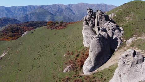 Mountain-aerial-flies-along-weathered-granite-outcrops-on-summit-slope