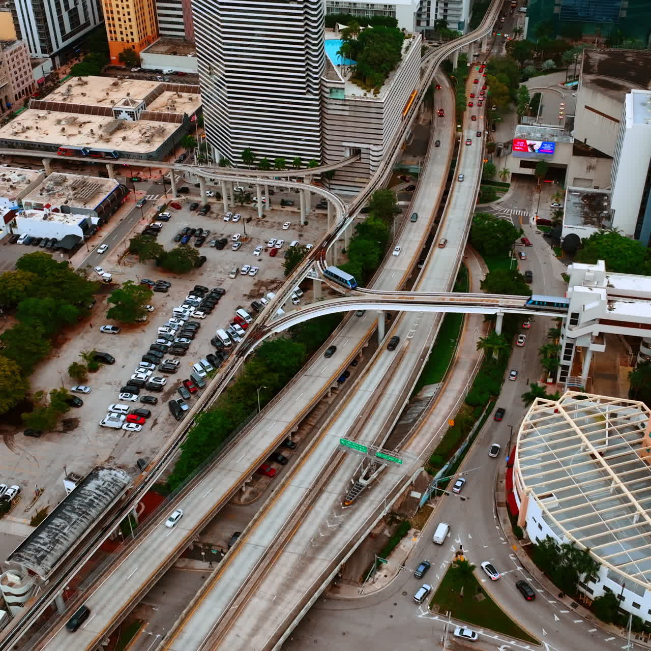 Drone footage approaching the roads and tram rail in the district of Miami, Florida, USA. Parking lot with lots of cars in centre.