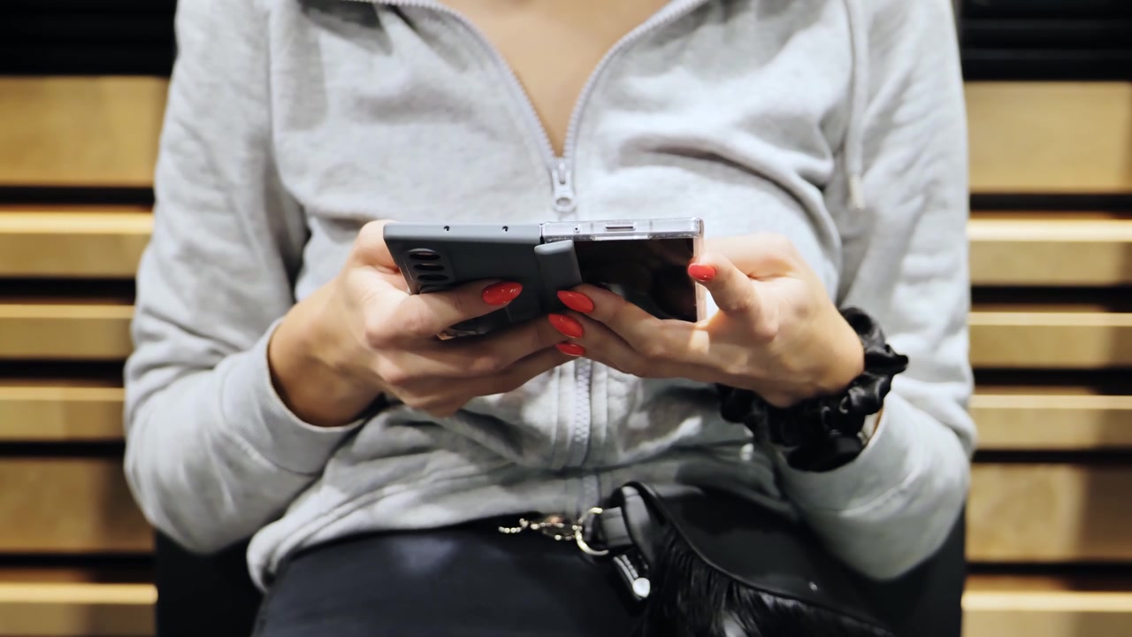 Donna usa smartphone pieghevole mentre aspetta il suo volo all'aeroporto