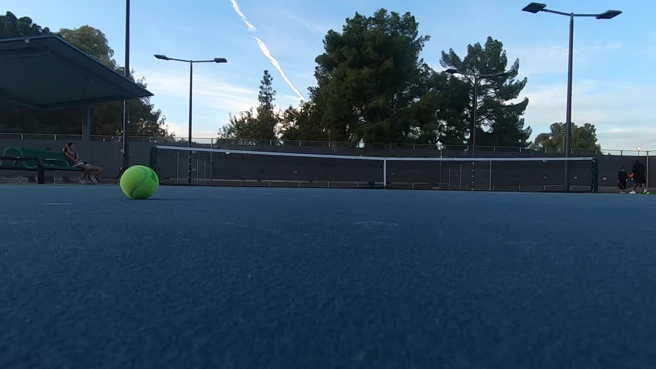 A tennis ball rolls into the ad-court then is picked up.