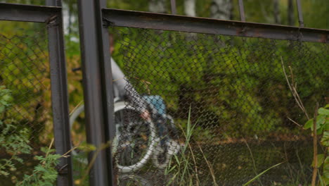 woman in wheelchair moves near old fence of sanatorium