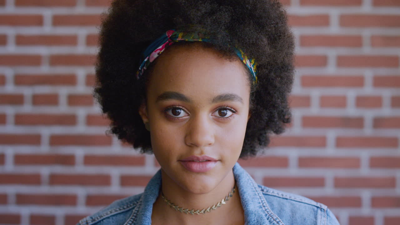 mujer negra, pared de ladrillo y sonrisa en la cara