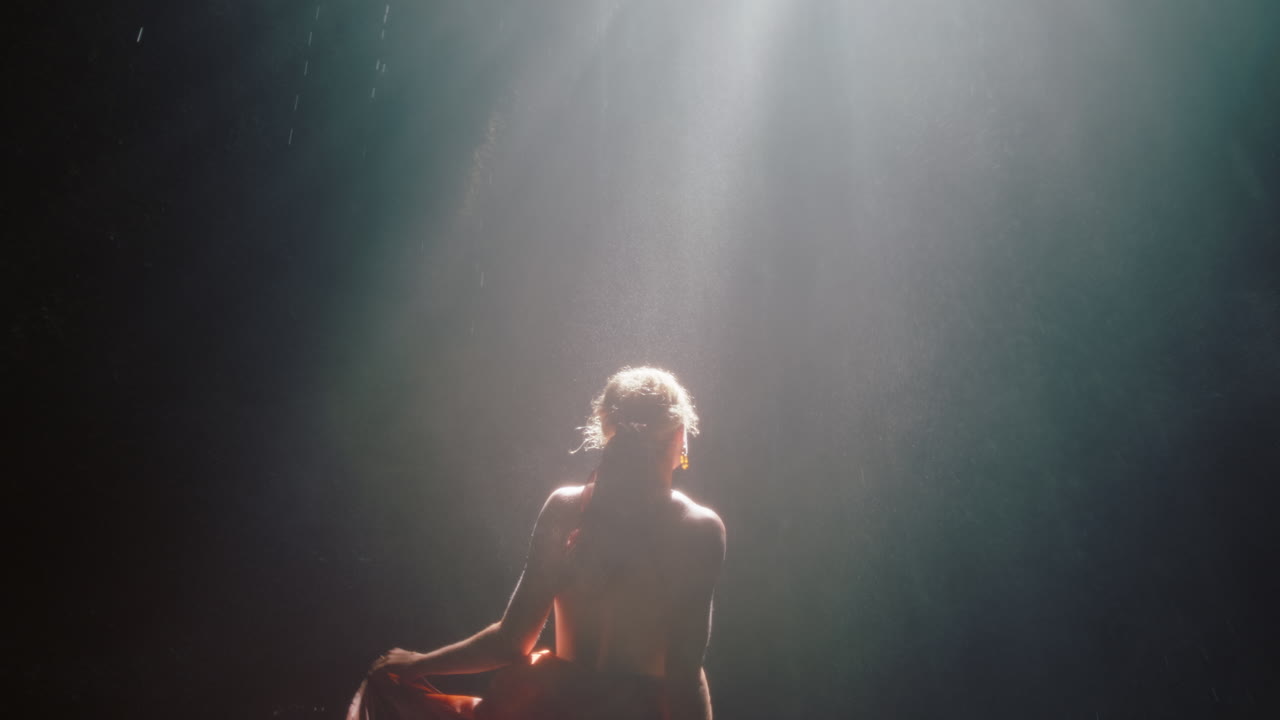 hermosa mujer bailando en la cueva de la cascada con un hermoso vestido disfrutando de la danza sintiendo libertad espiritual 4k