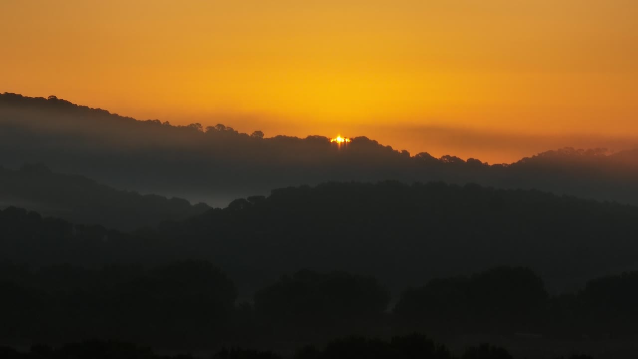 el lapso de tiempo de un amanecer de color naranja dorado sobre las exuberantes colinas de la vall