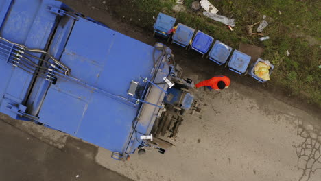 Toma-Aérea-De-Arriba-Hacia-Abajo-De-Los-Recolectores-De-Basura-Haciendo-Que-Los-Contenedores-De-Basura-Funcionen-Y-Recogiendo-Basura-En-Un-Camión