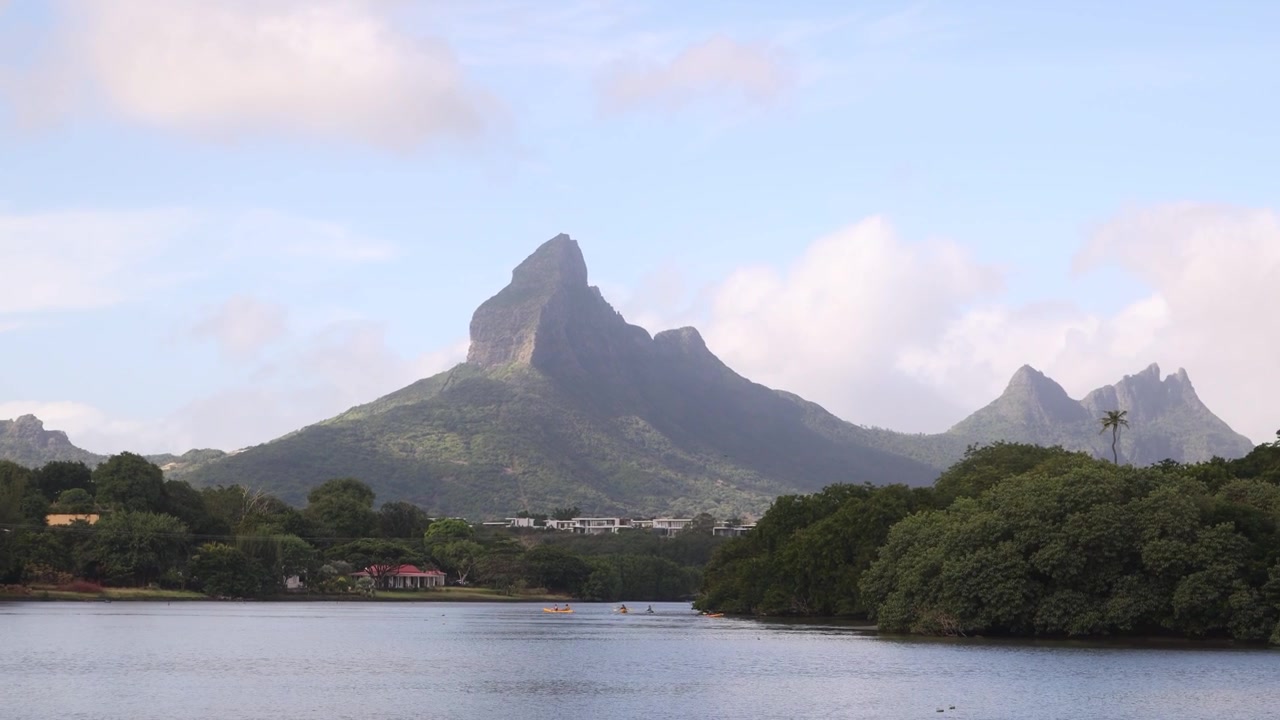 Vista panoramica delle montagne Trois Mamelles che si ergono su un fiume calmo e sponde verdi lussureggianti a Mauritius. Paesaggio di isola tropicale con drammatiche cime vulcaniche.