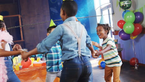 animation of red shapes spinning over children dancing, having fun at party