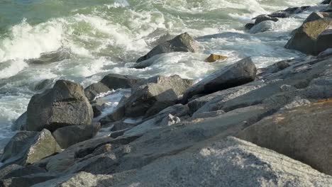 waves crashing against the breakwater rocks in sunny day