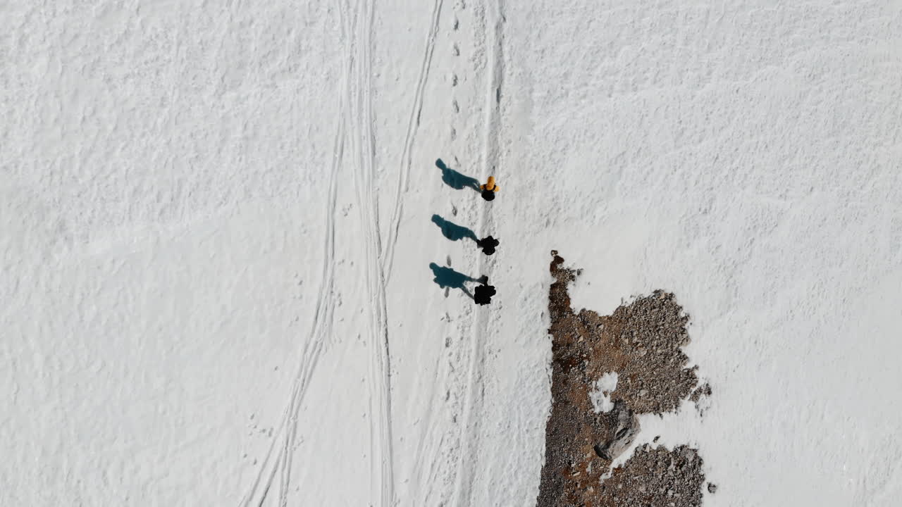 Vista aerea di tre persone che camminano su un sentiero innevato