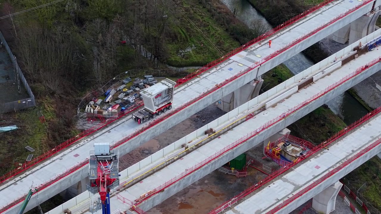 Vista aérea de um segmento maciço de viaduto HS2 de concreto pré-moldado sendo lentamente movido por uma unidade de transporte pesado especializada em Coleshill, Warwickshire, Reino Unido