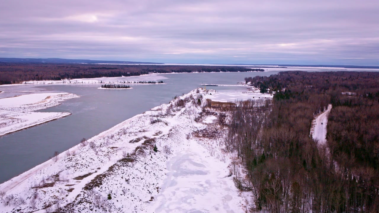 Dronekuva osittain jääpeitteisestä Yläjärven lahdesta, alapuolella levittäytyvän hiljaisen talvimaiseman kera.