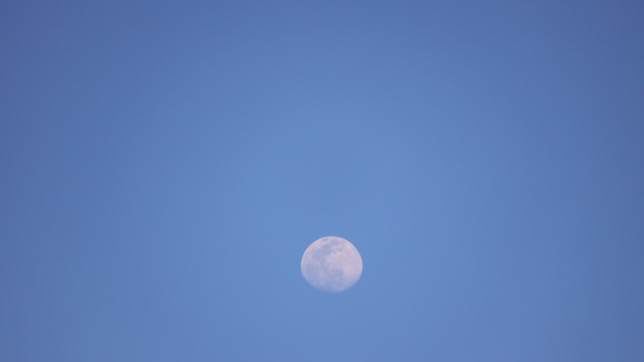 파란 밤 하늘을 가로질러 움직이는 밝은 보름달의 시간 간격 클로즈업.