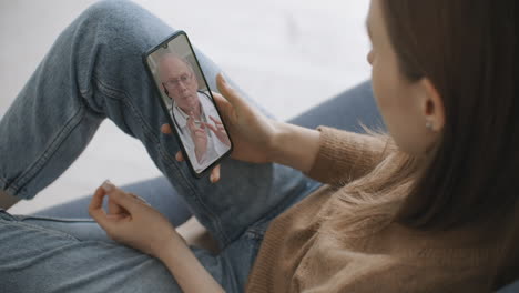 female medical assistant wears white coat headset video calling distant patient on smartphone. doctor talking to client using virtual chat telephone app. telemedicine remote healthcare services