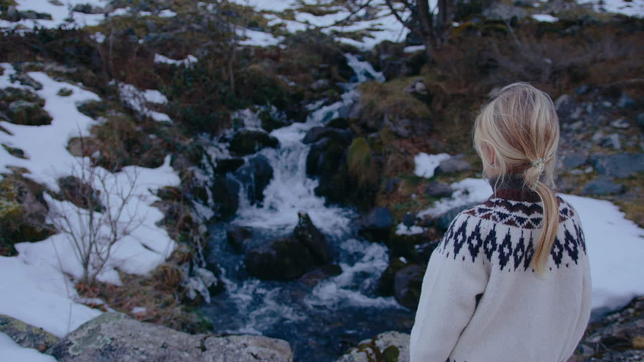 Woman looking at a winter mountain stream