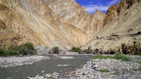 tilt up shot of a narrow river, to bald high mountains in the wilderness