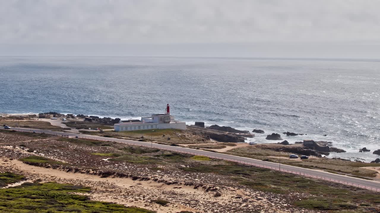 Coastal view of a lighthouse and road in Portugal under cloudy sky
