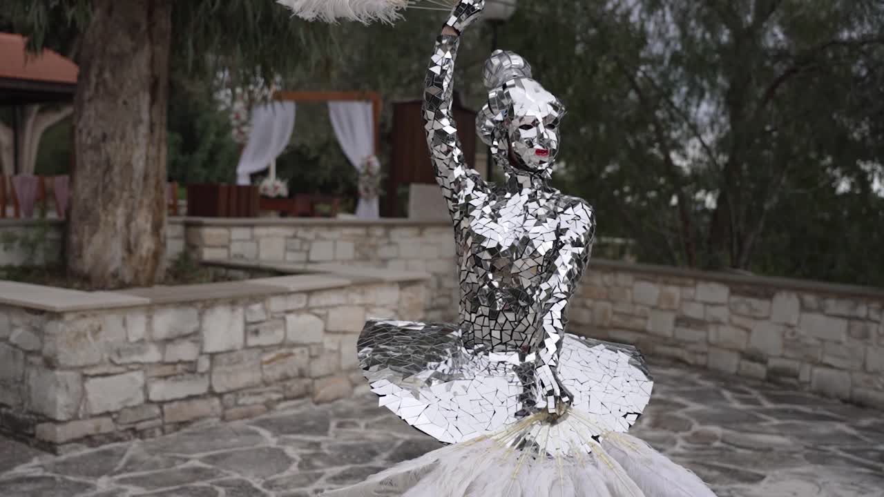 Mirror costume performer dancing with feathers outdoors in daylight