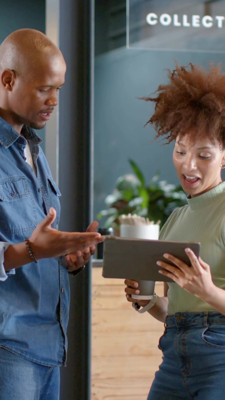 Vertical video: Tapping tablet, woman in green top holding cup, presenting at counter, man pointing
