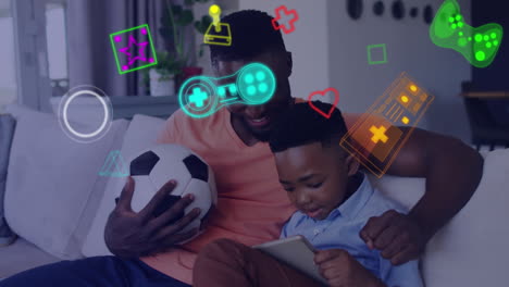 animation of game media icons over smiling father and son using tablet on couch at home