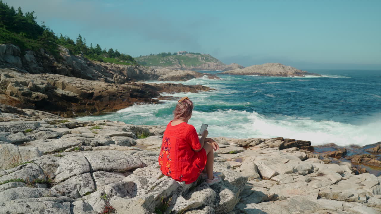 mujer vestida de rojo mirando la costa este de canadá durante el día