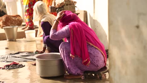 unrecognizable indian women with head covered by typical veil washing clothes outdoors, india. handheld