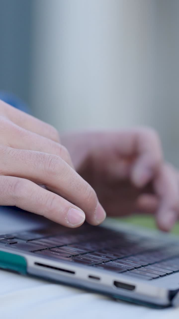 Programmer writing code on laptop keyboard. Vertical