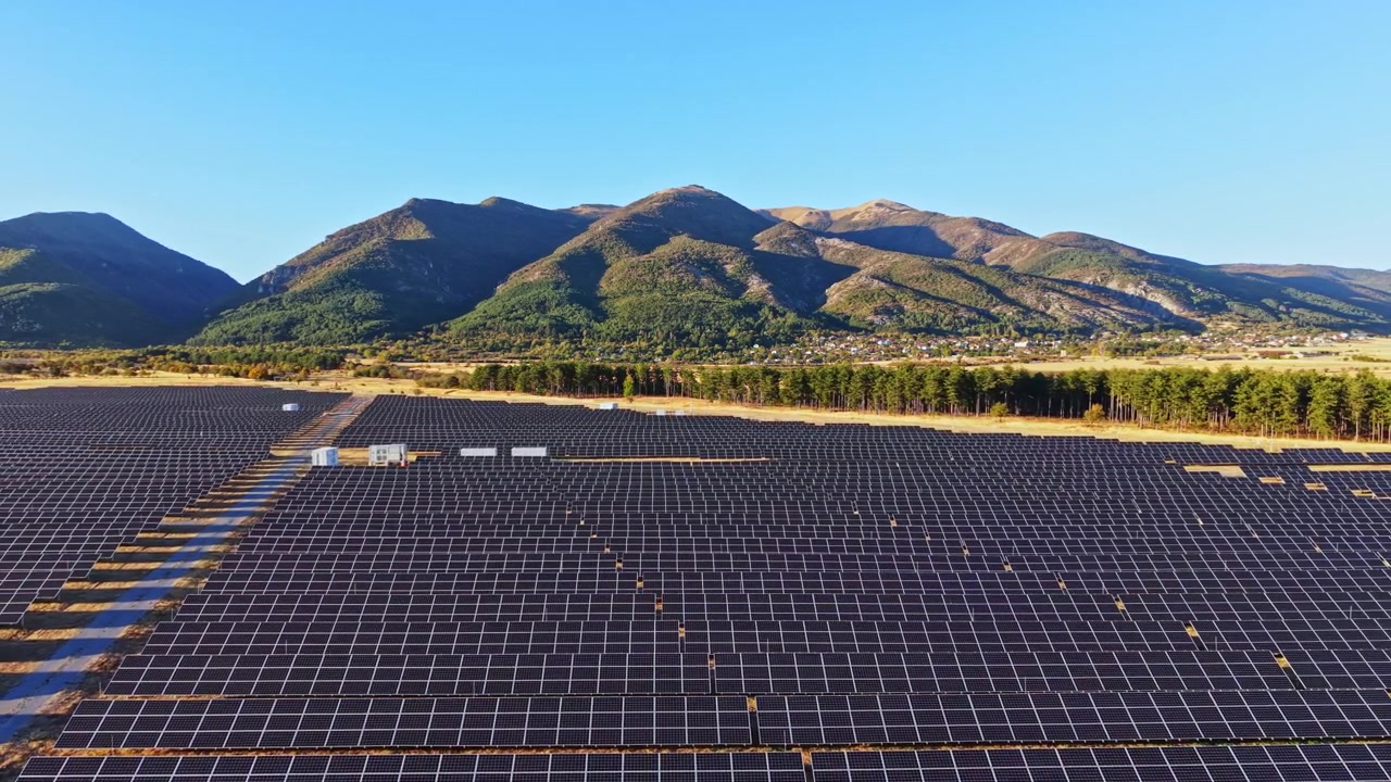 晴れ渡る青空の下、山々を背景に広大な敷地に設置された太陽光パネル
