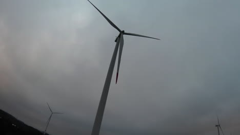 wind turbine spinning under cloudy sky low angle fpv