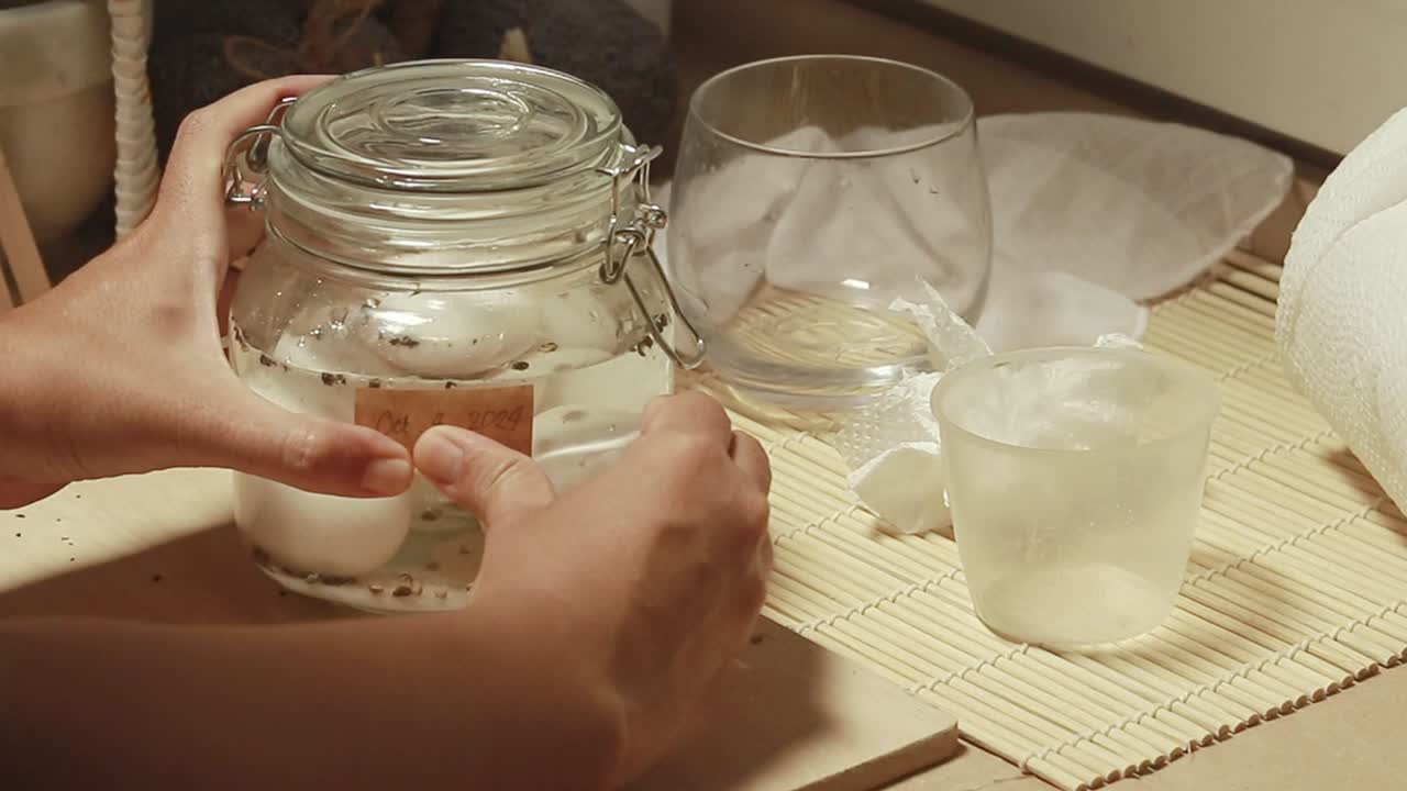 Attaching a label for the date on a jar of freshly made salted egg in a mason jar