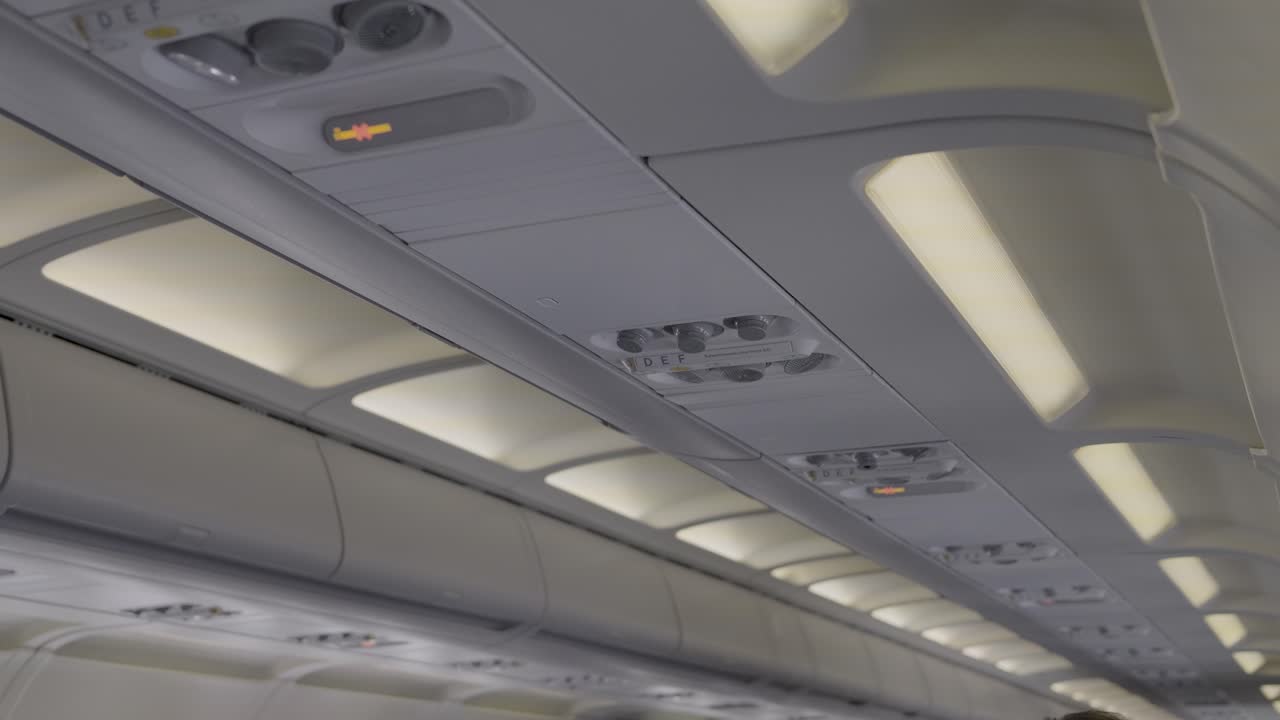 Cabin view from an airplane, showing overhead lights and air conditioning controls