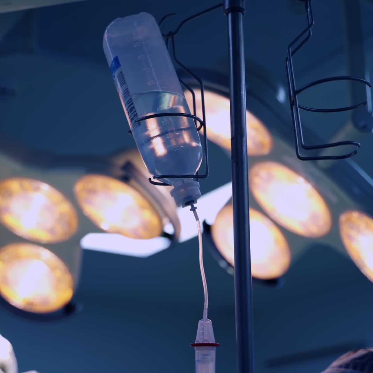 Plastic bottle of transparent liquid medicines in the drop counter. Turned on lamps in the surgery room at backdrop in blur